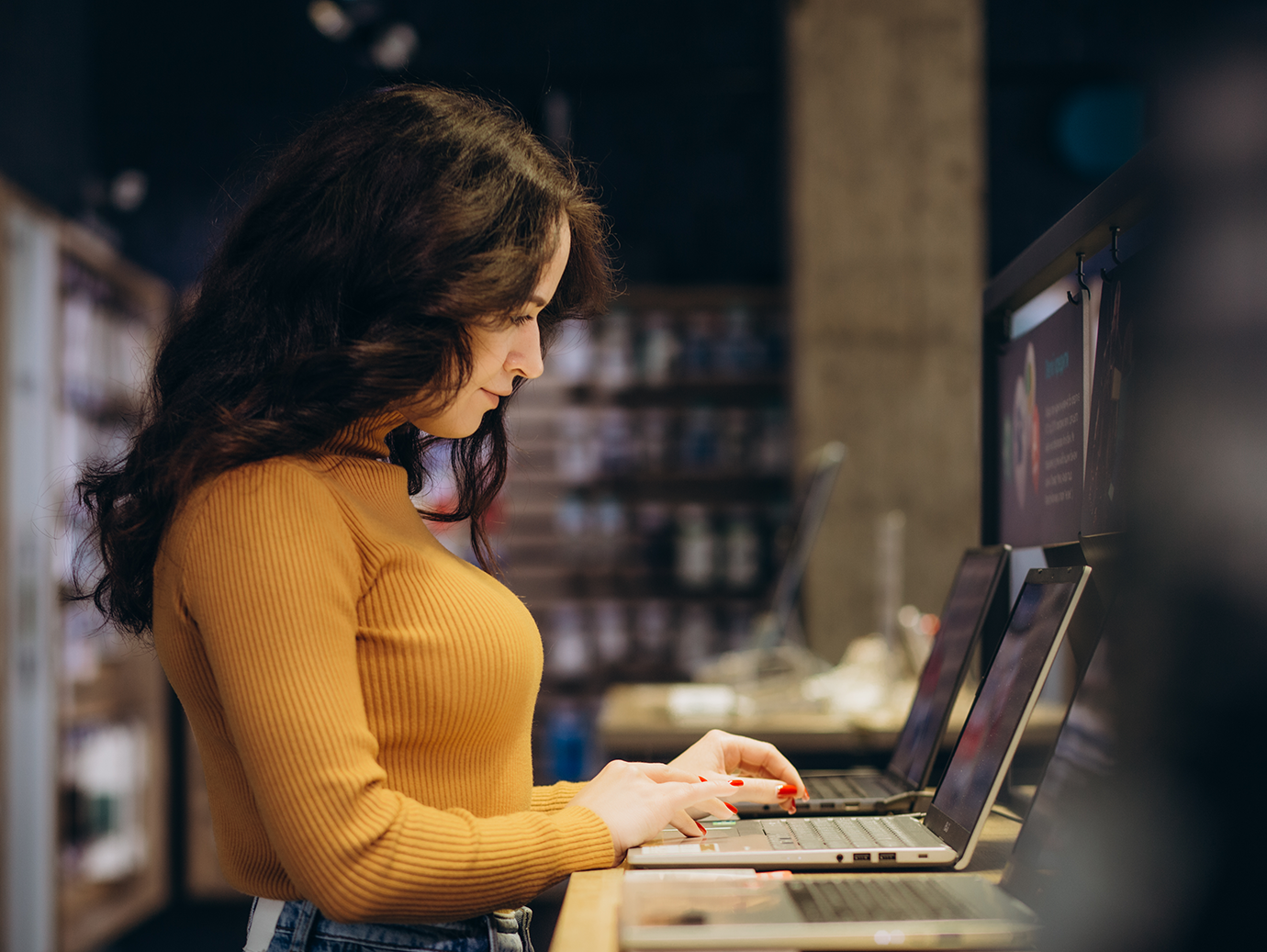 Side view of a woman trying a laptop in an electronics store